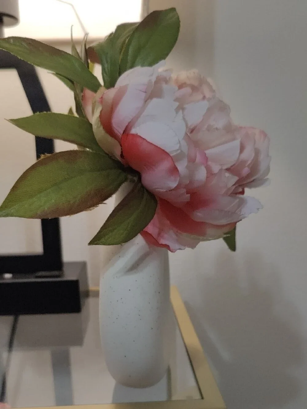 White Donut Ceramic Vase with Beautiful Pink Peony Flowers and Green Leaves.